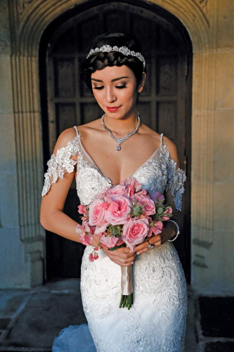bride in wedding dress holding flowers wooden door